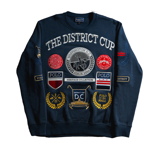 Navy crew neck sweatshirt from The District Cup Heritage Collection featuring embroidered District Cup iconography, Washington D.C. emblems, and ‘Polo on the Mall’ event patches.